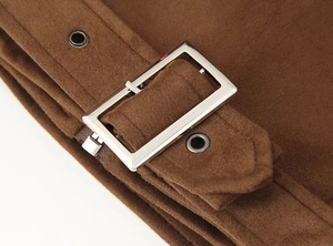 Macro detail of dark brown suede fabric with silver metal buckle and dual eyelets