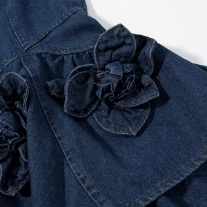 Close-up of denim dress showing layered floral applique and contrast stitching