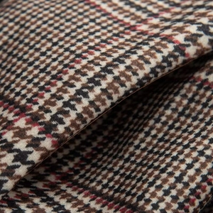 Close-up of multicolored houndstooth tweed fabric texture with woven red and cream patterns