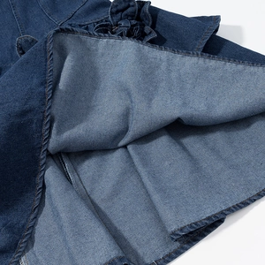 Macro detail of dark blue denim dress hem with yellow contrast stitching and twill texture