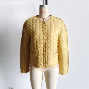 Detail of mustard yellow quilted jacket featuring square stitching and button closure