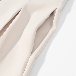 Detail van de zijzakstiksels en gladde stoftextuur op de beige mouwloze kledingset