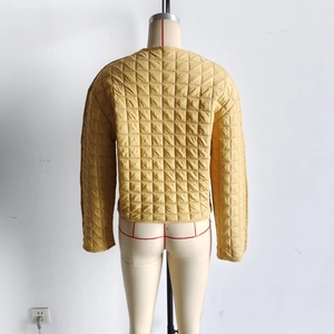 Detail of mustard yellow quilted short jacket with classic square stitch and round neck
