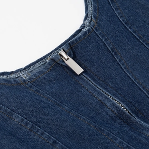 Detailed close-up of dark blue denim dress featuring silver zipper and yellow contrast stitching