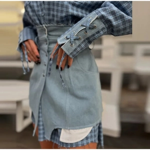 Detail of plaid shirt dress with lace-up denim sleeves and high-waisted button skirt