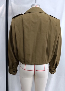 Detail view of khaki short trench jacket with back pleat design and epaulettes on shoulders