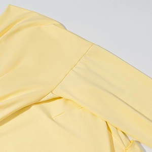 Close-up of the shoulder seam and ribbed knit fabric of a yellow off-shoulder dress