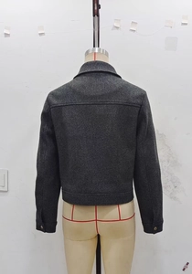Detail of dark grey short tweed jacket featuring a classic collar and back view texture