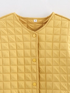 Detail of yellow quilted jacket neck with size label and matching round snap buttons