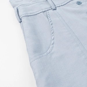 Détail de la texture du tissu en lin bleu clair avec poche et bouton de ceinture