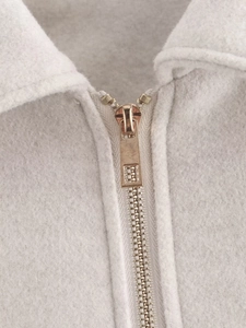 Close-up of rose gold metal zipper and textured light grey tweed fabric detail