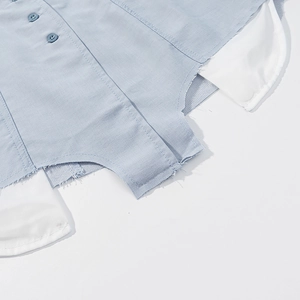Detail of light blue plaid shirt with raw hem and dark buttons on textured fabric