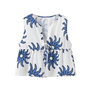 Detail of V-neck white sleeveless top with blue sunburst print and ruffle hem