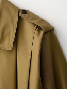 Detailed macro view of khaki trench coat shoulder epaulette with matte black button