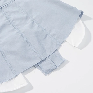 Gros plan détaillé de la jupe en jean bleu clair avec ourlet effiloché et patchwork blanc