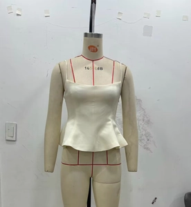 Detailed close-up of a white peplum camisole with thin straps and a square neckline