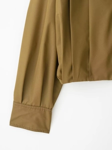Detailed view of sleeve stitching and pleated design on this khaki long-sleeve jacket