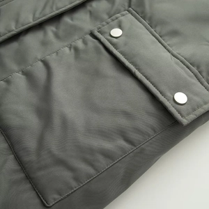 Detailed macro shot of the thick parka jacket fabric with large flap pocket and silver snaps