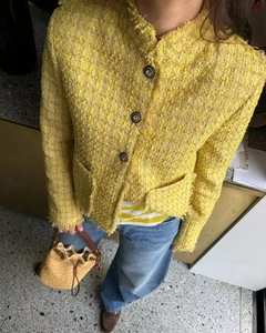 Détail de la veste en tweed jaune avec boutons rétro en relief et bords à franges