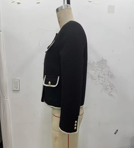 Detailed side view of black tweed jacket with white braided trim and golden buttons