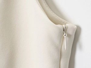 Detail of the invisible zipper and textured fabric on the white sleeveless top