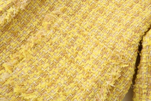 Gros plan du tissu en tweed jaune avec bords à franges et texture tissée