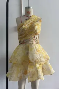 Détail d'une robe fleurie jaune à une épaule avec découpe à la taille et bordure crochet