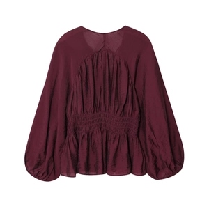 Detail of burgundy long sleeve blouse showing pleated waist and silk texture fabric