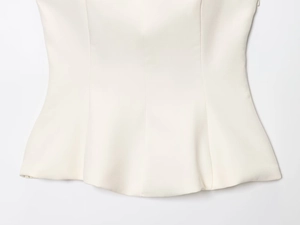 Detailed macro view of cream peplum top featuring precise vertical princess seam stitching