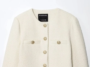 Detail of tweed fabric texture and gold embossed buttons on a beige French jacket