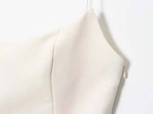 Detailed macro view of cream-colored top featuring slim straps and invisible side zipper