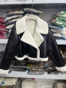 Detailansicht der schwarzen Kunstlederjacke mit weißem, flauschigem Lammfell-Innenfutter