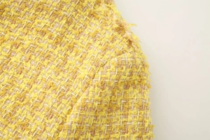 Vue macro détaillée de la texture du tissu en tweed jaune d'une veste femme chic