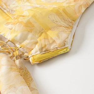 Détail d'une robe en mousseline fleurie avec fermeture éclair jaune et anneau en métal