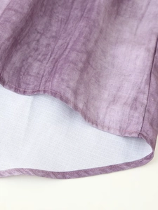 Detail of purple tie-dye linen dress hem showing natural fabric texture and neat stitching