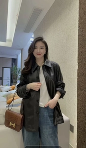 Detail of a black faux leather jacket paired with a luxury textured shoulder bag