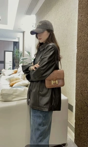 Detail showing a black faux leather jacket and a brown croc-pattern bag with gold buckle