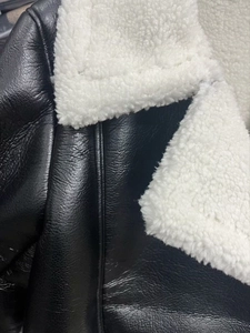 Detail aus schwarzem Kunstleder und weißem Sherpa-Futter an einer Fliegerjacke mit Fleece