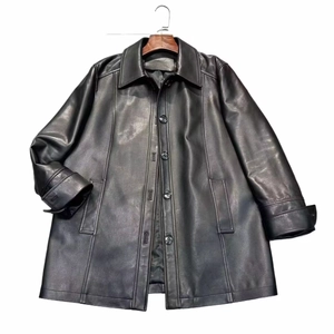 Detail of black leather coat featuring a classic collar and smooth buttoned front