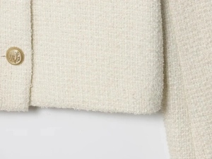 Detailed macro view of white tweed fabric texture and vintage gold crest button