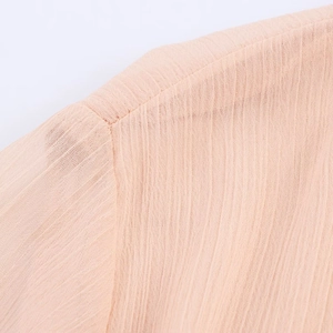 Close-up of light pink midi dress showing pleated fabric texture and stitching details