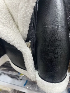 Detailansicht der schwarzen Kunstlederjacke mit weißem Lammfellimitat und Metallreißverschluss