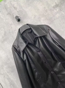 Close-up of black faux leather coat featuring a lapel collar and single-breasted buttons