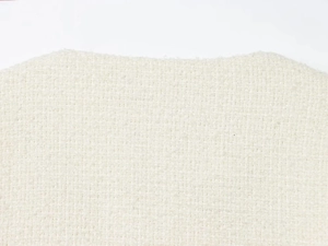 Close-up of the textured tweed fabric collar on a minimalist French style ivory jacket