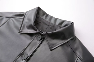 Close-up of black leather jacket showing lapel collar detail and round button closure