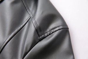 Detailed macro view of high-quality black leather jacket shoulder with reinforced stitching