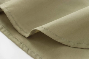 Detail view of precise stitching and high-quality poplin fabric on a grass green shirt