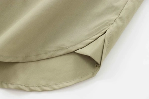 Detailed macro view showing the side split design and curved hem of the khaki poplin shirt