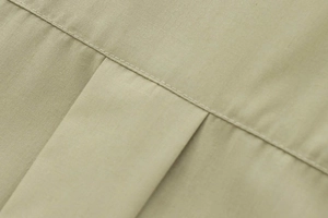 Macro shot of khaki poplin fabric texture showing fine stitching and pleat details