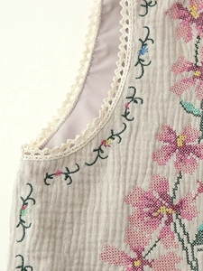 Close-up of floral embroidery on cotton smocked top with crochet lace trim details